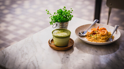 Glass of green tea and plate of spaghetti on marble table