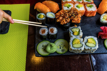 Sushi roll eating with chopstick. Sushi set restaurant. Black background. Japanese sushi food. Healthy food. Top view. Food set.