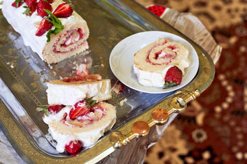 Cutting freshly baked sweet strawberry Long-Cake Roll, also called Strawberry roulade