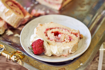 Cutting freshly baked sweet strawberry Long-Cake Roll, also called Strawberry roulade