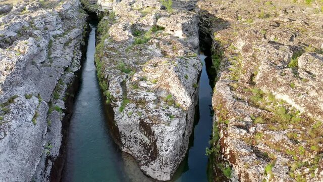 Fork of a narrow mountain river flowing through rocky landscape. Stream bed cut deep into rock. Upstream of Cijevna (Cem) in Montenegro. Aerial footage.