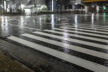 Water flows across crosswalk on empty street at night