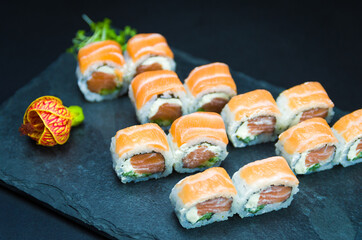 Sushi, traditional Japanese cuisine. Delicious Uramaki on decorated plate, black background.