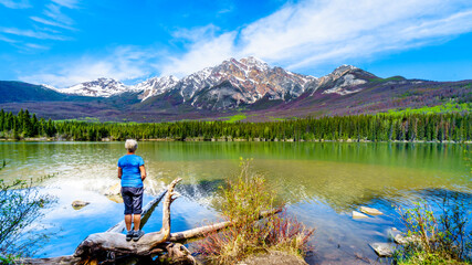 Senior woman looking at Pyramid Mountain in Pyramid Lake in Jasper National Park in Alberta, Canada. The mountains is part of the Victoria Cross Range in the Rocky Mountains