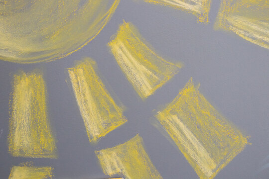 The sun drawn in yellow and white chalk on a gray chalk board,