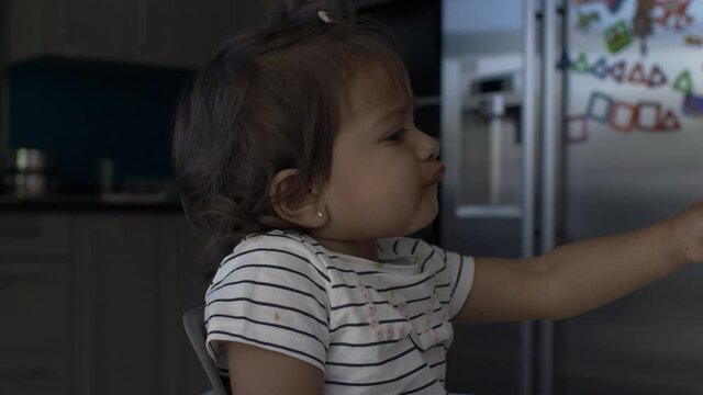 UK Asian Baby Being Fed Ice Cream Lolly Whilst On High Chair. Locked Off, Side View