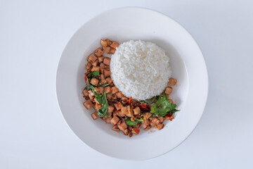 Rice topped with stir-fried ham cubes and basil on white background