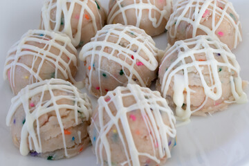 Birthday cake sprinkled edible cookie dough balls with vanilla drizzle plated and ready to be enjoyed.
