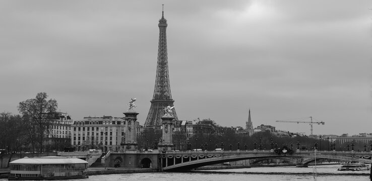 Moody panoramic cityscape with Pont Alexandre III bridge, Seine river and Eiffel Tower in Paris, France in black and white