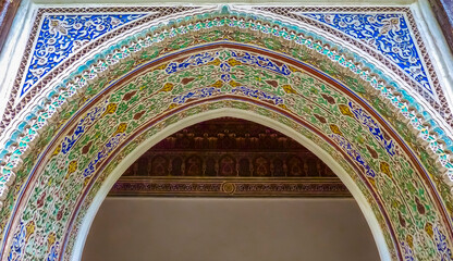 Colorful ornate arabesque plaster carvings above an archway in Moroccan riad
