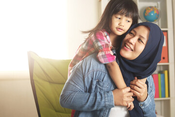 Muslim mother playing with her baby girl, mom and daughter love each other, happy single parent