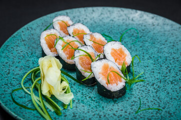 Sushi, traditional Japanese cuisine. Delicious hossomaki on the decorated plate, black background.