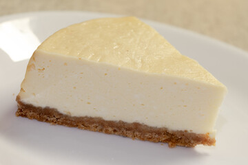 A slice of plain cheesecake on a white plate ready to be served.