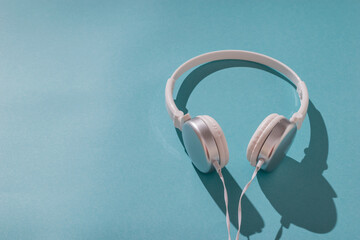 Headphones with a wire in hard light on a blue background.