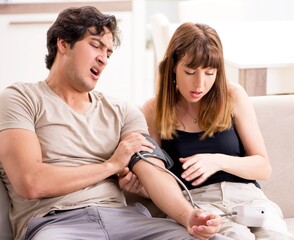 Wife checking husband's blood pressure