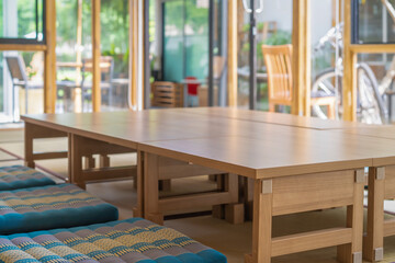 little small wood table are arranged for long table Japanese room style on the mat in glass room that prepare for lunch time.