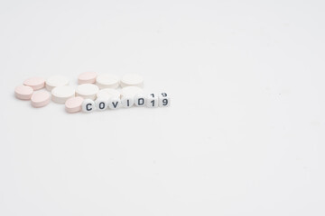 The word covid 19 with pills and syringes,over white background and surface