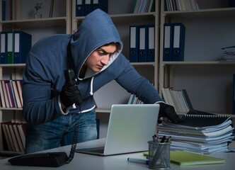 Young hacker hacking into computer at night