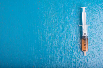 A syringe isolated over blue wooden background,