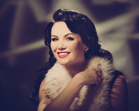 Portrait of gorgeous smiling woman posing in fashionable fur. retro style toned image
