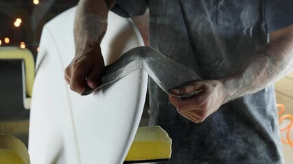Making a surfboard, Shaper sands the surfboard with a tool. Skilled professional craftsman at work, small business millennial entrepreneur in America. - Powered by Adobe