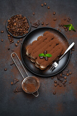 Classic tiramisu dessert on ceramic plate on concrete background
