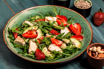 Plate with a keto diet food. strawberry salad with arugula, chicken, avocado and strawberries. Food recipe background. Close up