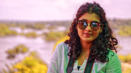Young Asian girl smiling to the camera. Blurred background of the River Nile. Portrait.
