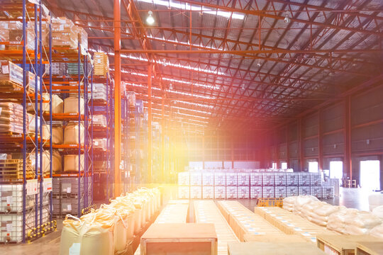 Large distribution warehouse interior, pallets, and boxes of cargo stack on row of high shelves.