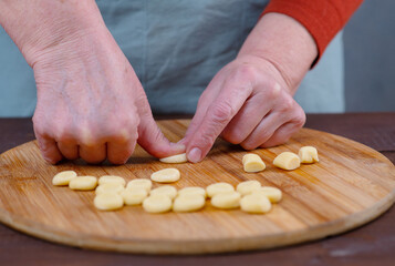 Hands of an elderly woman work with pieces of dest, making blanks for dumplings