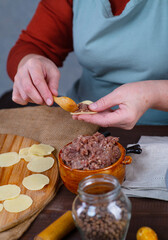 The cook puts the minced meat in the dough to create dumplings