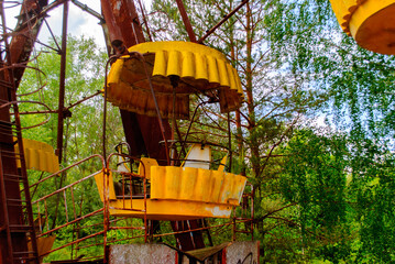 Fototapeta na wymiar Observation wheel carousel with yellow cabins in the former musement park in Pripyat, a ghost town in northern Ukraine, evacuated the day after the Chernobyl disaster on April 26, 1986