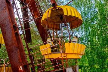 Fototapeta na wymiar Observation wheel carousel with yellow cabins in the former musement park in Pripyat, a ghost town in northern Ukraine, evacuated the day after the Chernobyl disaster on April 26, 1986