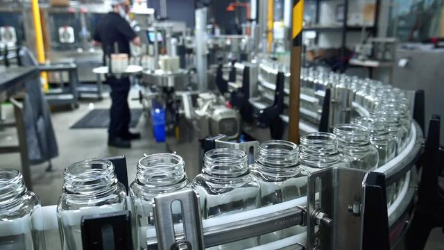 Industrial juice factory indoors machinery. Robotic automation line for bottling juice into glass bottles. packaging warehouse facility.