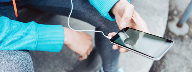 Woman runner using mobile phone on the street. Wide screen, panoramic