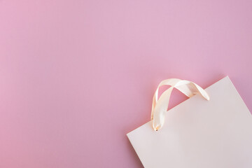 Paper shopping bag on pink background. Sales, discounts, presents and shopping concept. Top view, flat lay, copy space