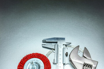 circular wire brush disk with studded diamond blade, adjustable wrench and caliper on gray metallic background