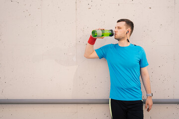 Profile view of sporty young man drinking water from bottle after long city run