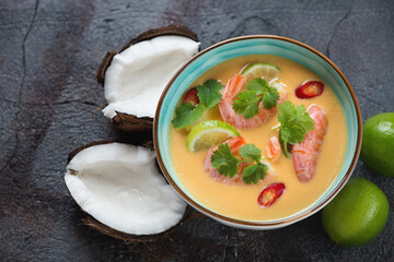 Bowl of thai-style pumpkin, coconut milk and prawn soup over grey asphalt background, horizontal shot
