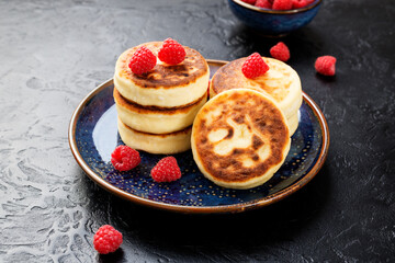Cottage cheese fritters or syrniki with fresh raspberries. Tasty dessert or sweet breakfast. Russian, Ukrainian cuisine food