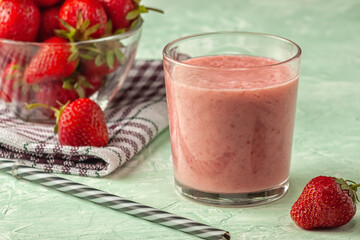 Strawberry smoothie with milk in a glass on a green background, healthy eating for breakfast and snacks