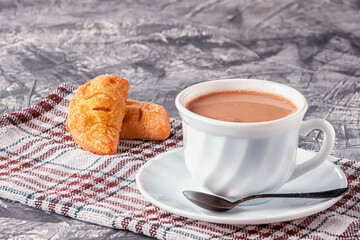Coffee with cream and freshly baked puffs on a gray background