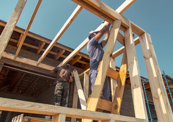 A worker measures a wooden workpiece with a meter.