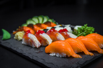 Sushi, traditional Japanese cuisine. Several delicious sushi on the decorated plate, black background. Group of sushi, Urakami, Nigori, Sushi jow, sashimi, tekamaki, etc ...