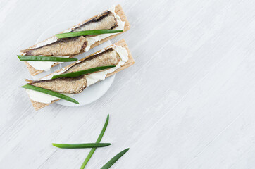 Fresh summer healthy appetizer of whole grain crisps breads with sprats preserves, green onion,...