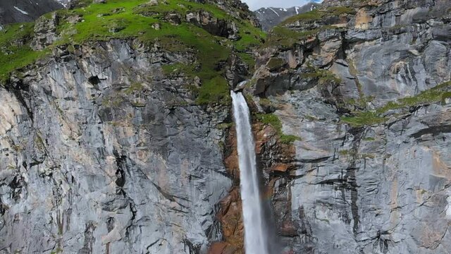 Aerial slow motion: drone flying over scenic high waterfall, mountain stream falling from tall rocky cliff on the italian Alps. Pis waterfall near Torino, Piedmont, Italy