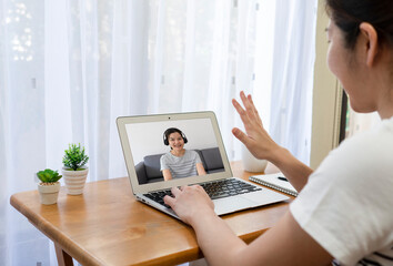 Fototapeta premium Asian business woman using computer to work from home via video conference with clients during covid-19 or coronavirus outbreak. technology and new normal lifestyle concept