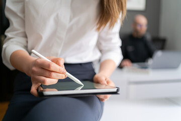 Business woman hands close up working with tablet in modern office wearing white shirt black pants