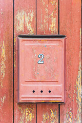 Red mailbox with number 2 on a red wooden wall
