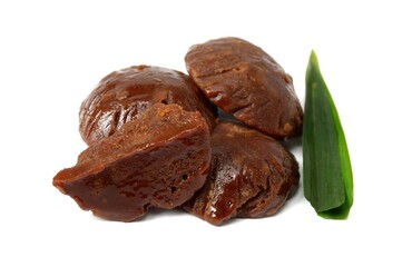 Organic brown palm sugar or coconut sugar, better known as Java sugar, sugar made from coconut juice with fresh green pandan leaves. Isolated on a white background